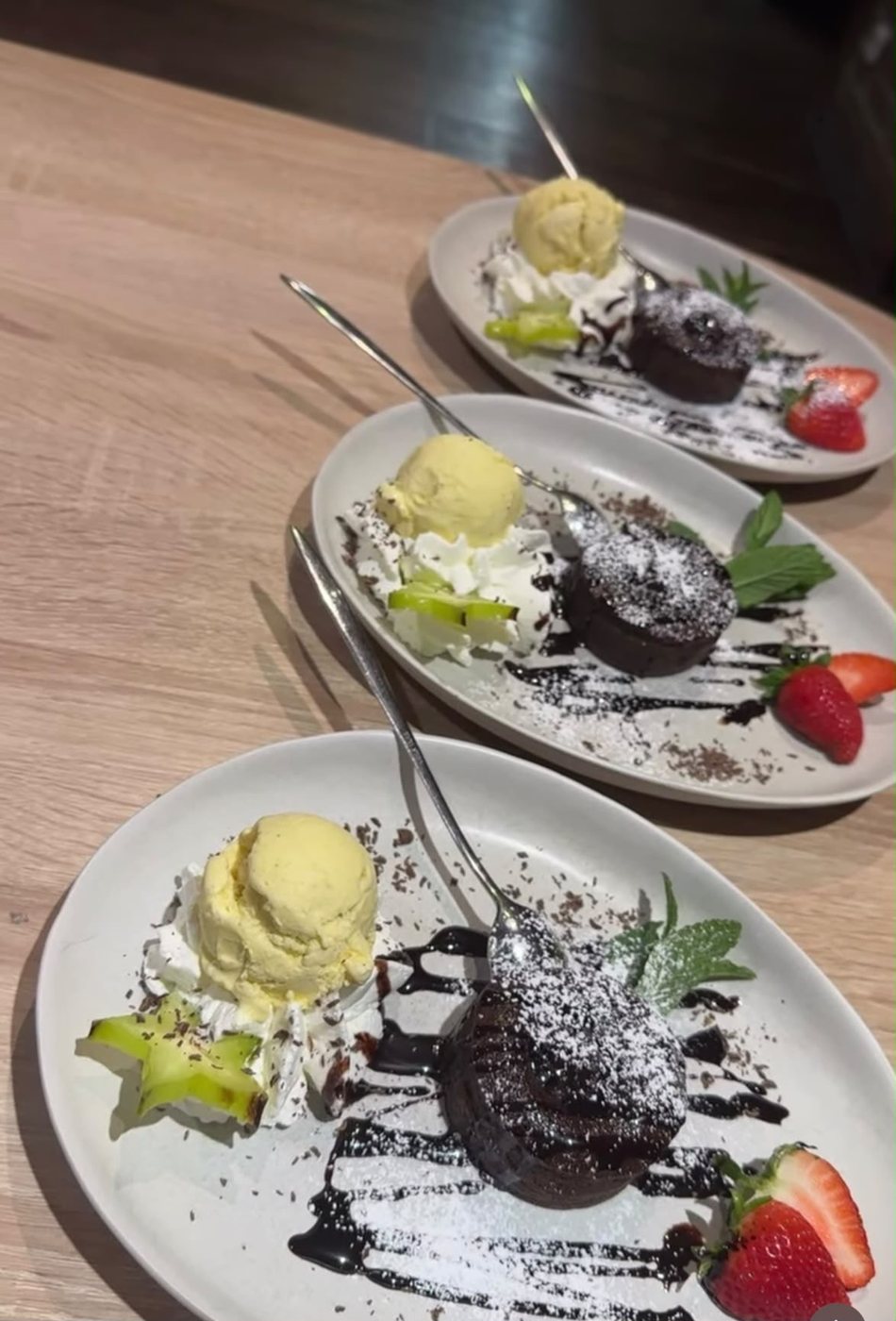 Drei Teller mit Schokoküchlein, Vanilleeis und frischen Erdbeeren