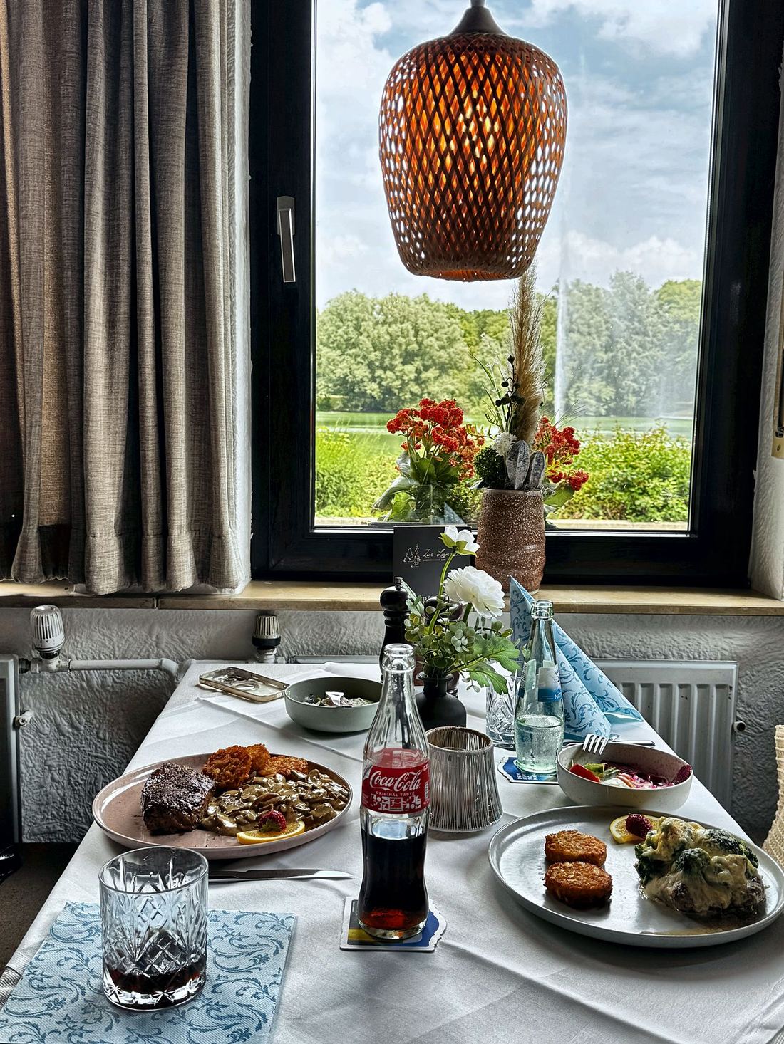 Ein gedeckter Tisch am Fenster mit Blick über den Teich zur Fontäne